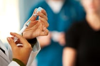 A medical professional prepares a syringe with treatment