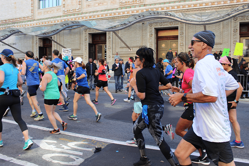 Joseph Buccino (right) smiles as he runs the 2018 NYC Marathon.