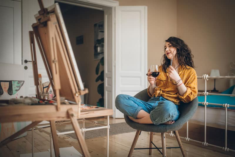 young woman drinks wine and paints