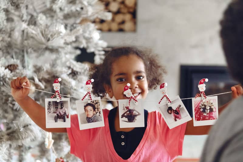 oung girl holding family photos to decorate tree