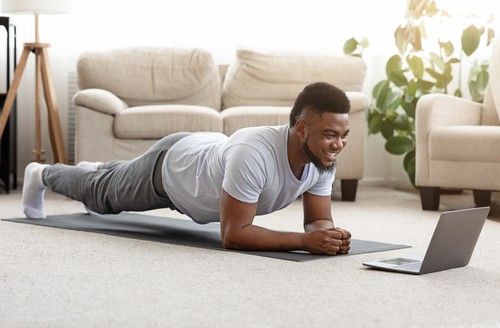 African American man wearing white and planking