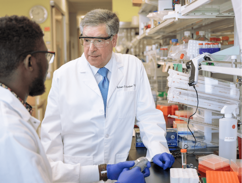 Robert D. Schreiber, PhD, and Samuel O. Ameh, a doctoral student in his lab at Washington University. (photo provided by the Washington University School of Medicine)