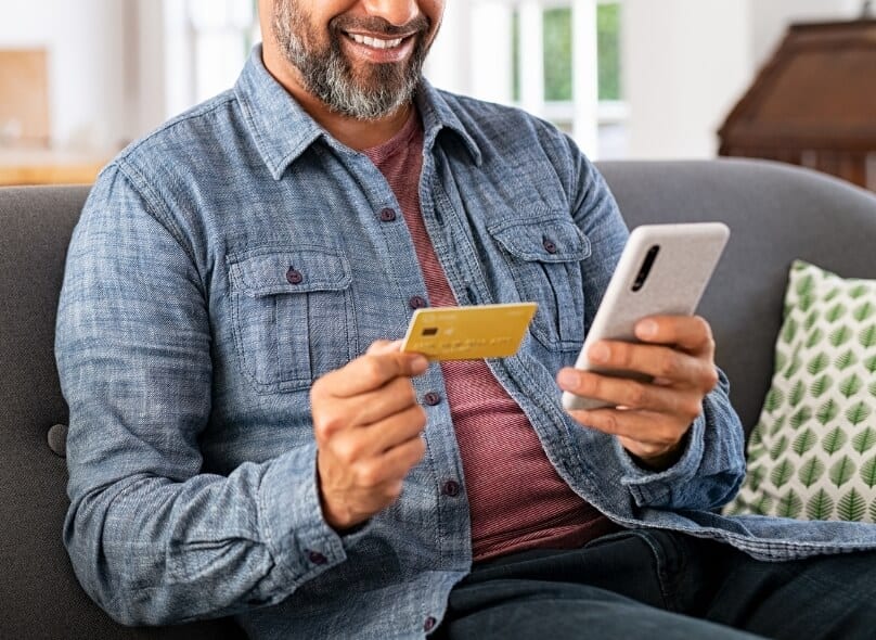 Man holding up a credit card and a phone