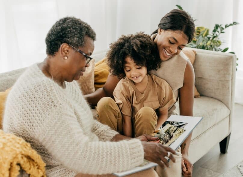 A family sits on a couch and looks at a book