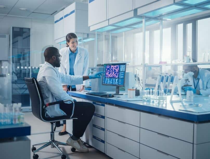 Two scientists discuss what's displayed on a computer monitor inside a lab