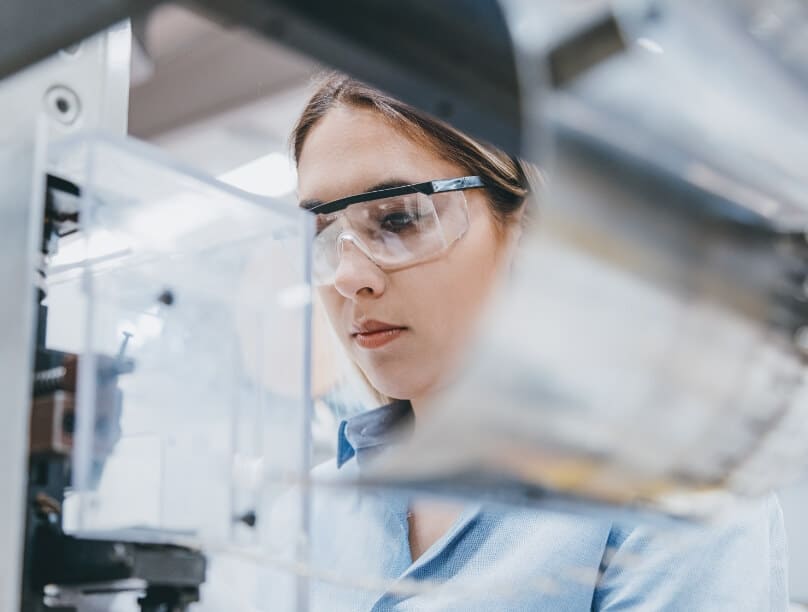 A scientist with safety goggles works in a lab