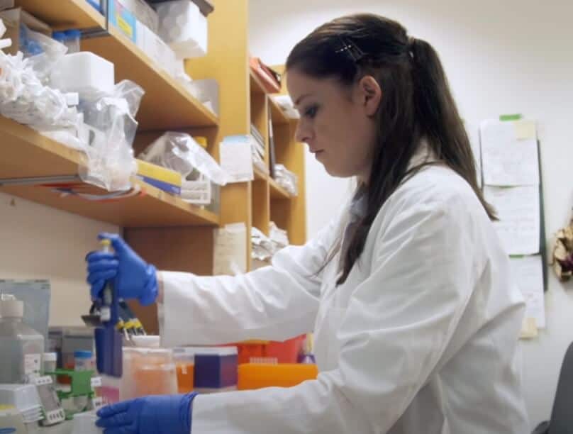 Scientist with gloves on stands and works at a lab