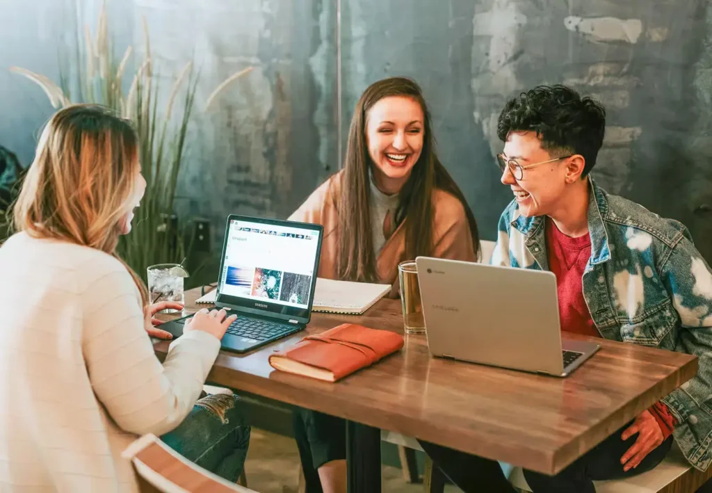 A group of colleagues working with their laptops laughing.